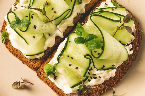 Breakfast, cereal bread sandwiches, cream cheese, sliced cucumber, with micro greenery on a light