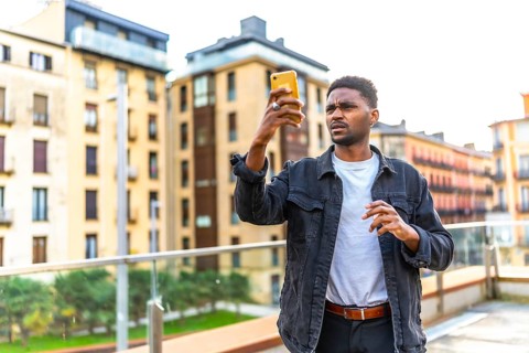 African handsome young man looking for direction using smartphone in the city