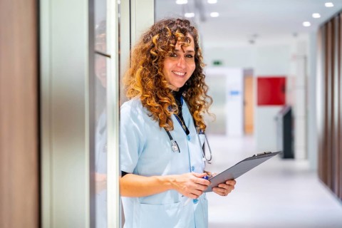 Portrait of a nurse holding a medical record smiling at camera
