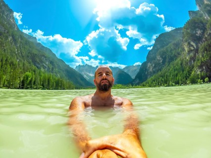 Tourist swimming in the crystal clear waters of lago di landro, surrounded by the breathtaking