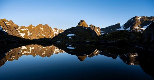Rocky mountain peaks reflected in a small pond, mountain landscape with alpenglow at sunrise, at