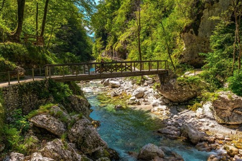 Turquoise water flowing under wooden bridge over tolmin gorges in triglav national park, slovenia