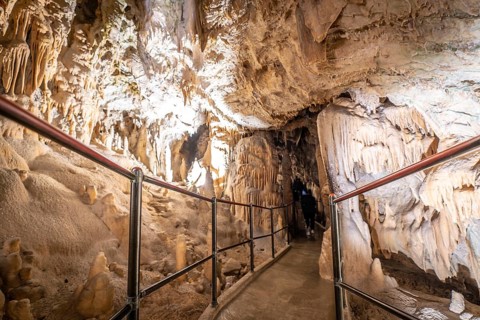Tourists walking on a footpath and exploring the magnificent postojna cave in slovenia, a popular