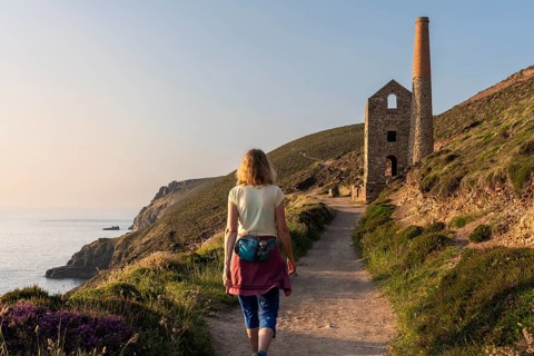 A hiker on the trail to the ruins of Wheal Coates, a former tin mine. The Towanroath Shaft. Pink