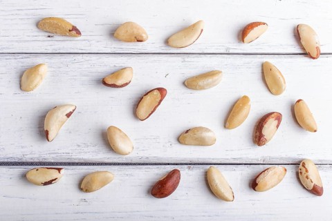 Pattern and texture made from Brazil nuts on white wooden background, flat lay. top view