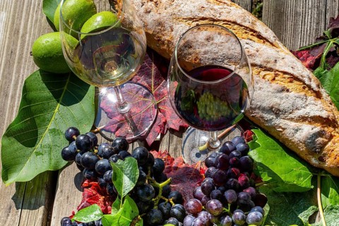 Symbolic image of grape grape harvest: Ripe grapes decorated with wine glasses on a wooden table