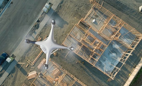 Unmanned aircraft system quadcopter drone UAV in the air over construction site.