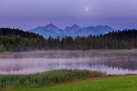 Foggy lake at dawn with visible mountains and forests, quiet atmosphere, Hegratsrieder See near