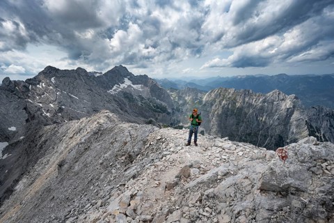 Mountaineer with helmet on a narrow rocky path, crossing the Jubiläumsgrat, view of Zugspitze and