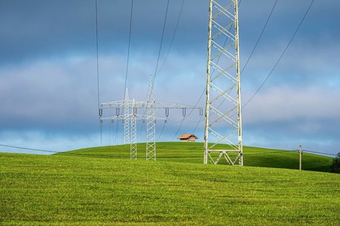 Powerlines of local hydroelectric power station dominate the landscape, rural meadows, Roßhaupten,