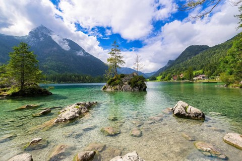 Hintersee near Ramsau with clear green water, surrounded by forests and mountains under a cloudy