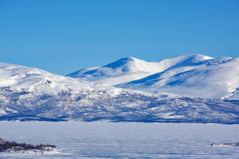 Snow-capped mountains and a frozen lake under a clear blue sky, Abisko, Abisko National Park,