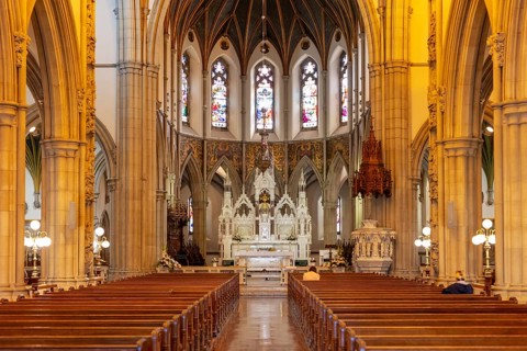 Magnificent interior of a church with a view of the altar and ornate Gothic arches under a warm