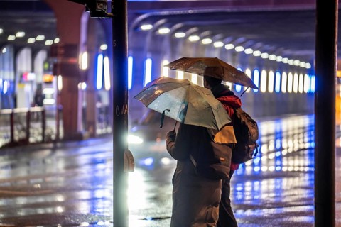 Illuminated subway at the main railway station, pedestrians at a pedestrian crossing, rainy