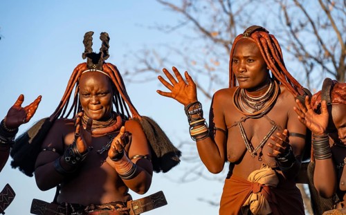 Traditional Himba woman clapping, music and dance, portraits, in the evening light, near Opuwo,