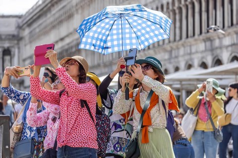 Tourists from Asia with mobile phones and parasols taking photos. Souvenir photo of St Mark's
