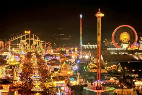 Street of beer tents, main street at night with illuminated roller coaster, Ferris wheel, stalls,