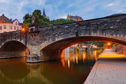 Town view of Vianden with the old stone bridge over the river Our and the castle in the evening,
