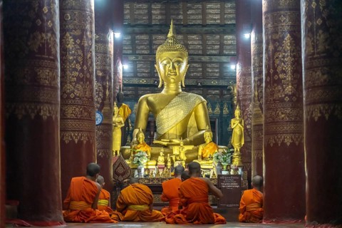 Monks praying in front of the great Buddha in the temple Wat Pak Khan Khammungkhun, Luang Prabang,