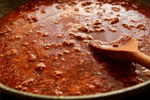 Cooking, bolognese sauce, in a frying pan, stirring with a wooden spoon, tomato meat sauce,