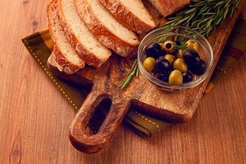 Sliced ciabatta, on a chopping board, with rosemary and olives, Italian bread, close-up, Italian