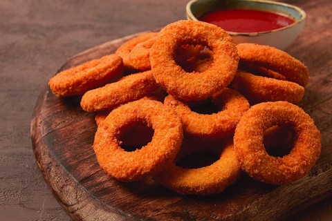 Crispy chicken rings, fried, on a wooden board, close-up