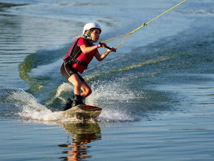 Boy or girl with wakeboard in the lake, red waistcoat, water sports, water skiing in the wake park
