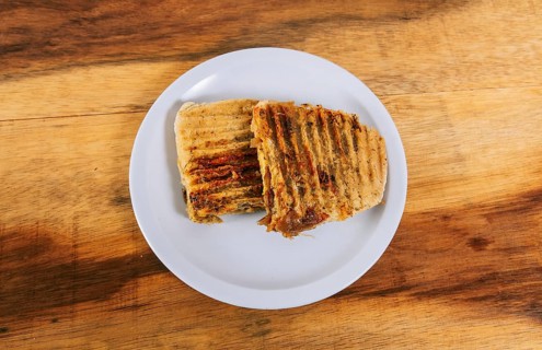 Top view of two meat and chicken panini on wooden table