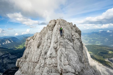 Mountaineer on a narrow rocky ridge on a steel cable, Watzmann crossing to Watzmann Mittelspitze,