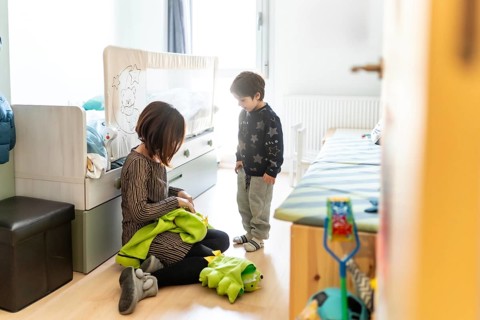 Mother and son playing together at home, preparing a dinosaur costume for a fun game in their