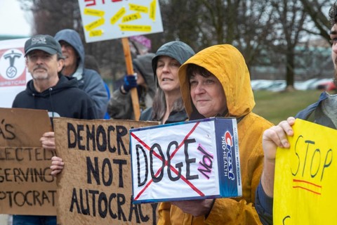 Troy, Michigan USA - 29 March 2025 - People gathered in the rain outside the Tesla Showroom at the