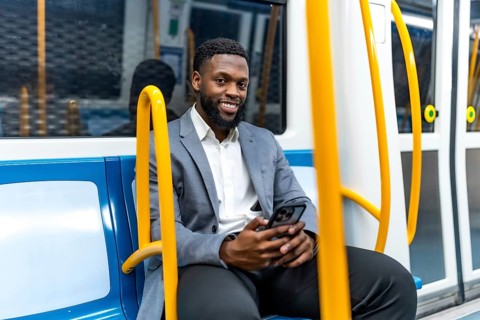 Young professional enjoying his commute, using a smartphone while traveling through the metro,