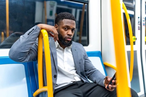 Young businessman engaging with smartphone while commuting on subway train, navigating messages and