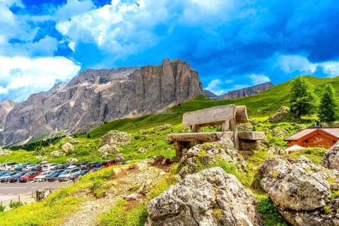 Weathered wooden bench inviting rest while offering breathtaking views of sella pass in the italian