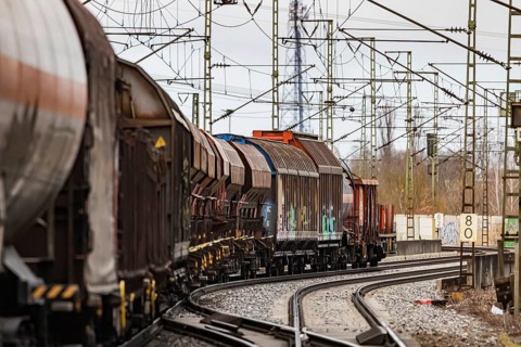 Goods train travelling on the winding Schuster Railway, overhead lines and infrastructure.