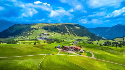 Stunning aerial view capturing green meadows, traditional houses, and rolling hills beneath a