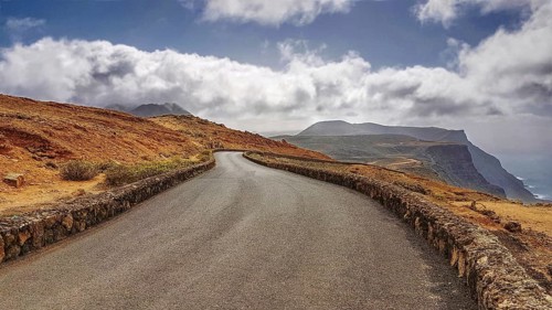 Serpentine road in a barren mountain landscape with clouds in the sky near the Mirador del Rio,