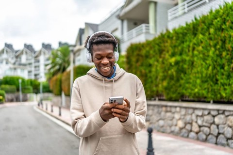 African young man using phone and listening to music in the city