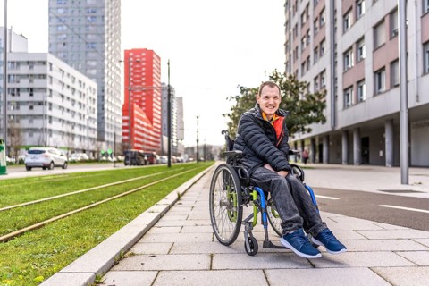 Portrait of a happy young man with disability in a wheelchair enjoying a sunny day in the city