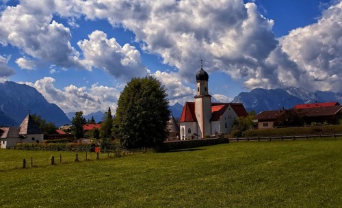 Idyllic village with church and mountains in the background under a blue sky, Wallgau, Bavaria,