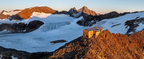 Atmospheric sunrise in a picturesque mountain landscape, alpenglow, aerial view, mountain hut