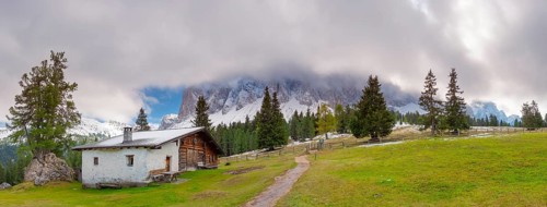 Panoramic view of the partly cloudy Geißler group with a hiking trail and a hut of the Glatsch Alm
