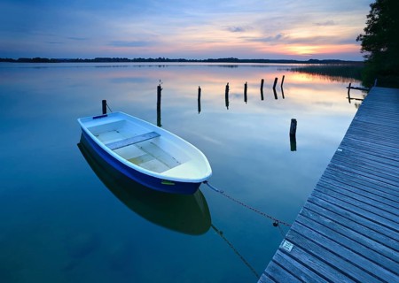 Sunset at Lake Schaalsee, jetty with rowing boat and wooden post in the water, Schaalsee Biosphere