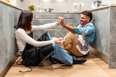 Chefs enjoying a coffee break, holding hands and smiling at each other, sitting on the kitchen
