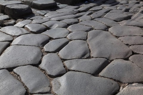 Close-up of large grey smooth and worn lava stones in a street at the ancient ruins of Pompeii,
