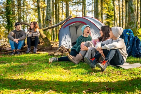 Caucasian family with three children sitting enjoying nature during a day camping at forest