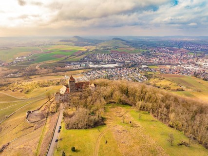 Aerial view of the castle with surrounding dense forests and a neighbouring village under a cloudy