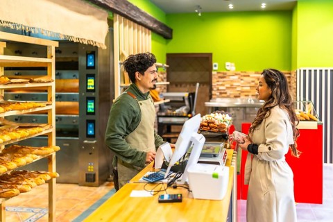 Elegant latin woman talking to salesman in a modern and artisan bakery