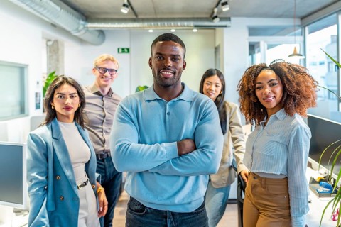 Diverse group of professionals standing together in a modern coworking space, showcasing teamwork