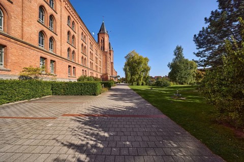 New town hall, brick building, architectural style neo-Gothic, former barracks, hedge, trees, blue